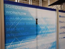 RENTAL: RE-2009 with Arch Canopy, Halogen Arm Lights, RE-1202 Reception Counter with Locking Door & Interior Shelf, (2) RE-1201 Counters, (2) RE-1223 Kiosks with Monitor Mounts, Tension Fabric Graphics, Sintra, Header and Counter Infill Graphic -- Image 4