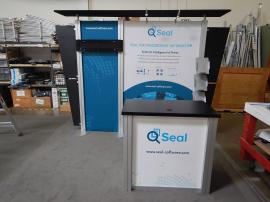 RENTAL: RE-1012 with Flat Black Canopy, (2) Arm Lights, Large Monitor Mount, (3) RE-170 Literature Shelves, RE-1202 Rectangular Counter, Tension Fabric Graphics, and Sintra Counter Graphic