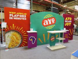 SYK-2020 Symphony Portable Display with SEG Fabric Graphics, Backwall Workstations, Wireless Charging Pads, (2) Monitor Mounts, (2) Literature Holders, SYM-404 Counter with Shelves, and LED Stem Lights