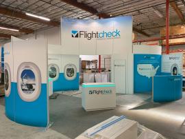 RENTAL: Modified RE-9106 Island Design with Curved Gravitee System Panels, Storage Closet with Locking Door, 16 ft. High Graphic Wall, (10) LED Arm Lights, Half Wall, (3) RE-1575 White Laminted Workstation Counters, RE-1576 White Laminted Reception Counte