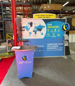 RENTAL: RE-1023 Inline Design with Black Laminated Workstation Counter, Adjustable Shelf, RE-1201 Black Laminate Reception Counter, (2) RE-170 Literature Shelves, Monitor Mount, (2) LED Arm Lights, Tension Fabric Graphic, and Vinyl Applied Graphic