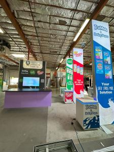 RENTAL: Modified RE-9085 Island Design with Storage Closet with Locking Door, and 12' High Front Wall, (3) 3' Wide x 15' High Double-Sided Lightboxes with Boomerang Baseplates, Large Monitor Mount with Internal Extrusion Supports, 65" Monitor with HDMI Ca