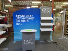 Modified VK-1362 Modular Exhibit with Tension Fabric Graphics, (3) Slanted Shelves, Backlighting, and SYM-406 Portable Counter with Locking Storage