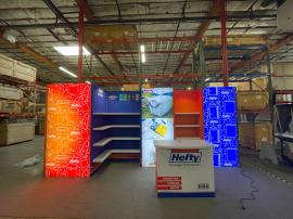 RENTAL: RE-2094 Gravitee Inline Design with Storage Closet, Backlit Gravitee Lightbox Panel, (1) White Lamintaed Shelves, RE-1558 Reception Counter, (3) LED Arm Lights, and SEG Fabric Graphics