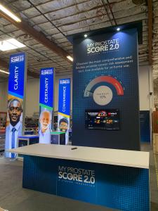 RENTAL: RE-9138 Island Design with 96" Wide x 190" High Gravitee Panel System Storage Tower with Locking Door, Black Laminate Soffits with Recessed Puck Lighting, Large Monitor Mount, (3) 3 ft. Wide x 15 ft. High Double-Sided Lightboxes with RE-1575 Works