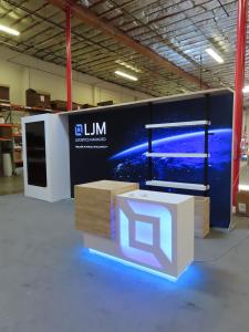 Custom Inline Exhibit with Vertical Monitor Mount Display, Backlit Fabric Graphic, Shelves, and Custom Counter with Backlit Logo and Locking Storage