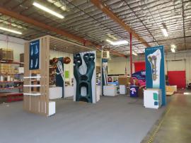 Custom Island Exhibit w/ Laminated Extrusion Canopy, Backlit Tension Fabric Graphics, (3) Hanging Ball Pendant Lights, (3) Shelves, (3) Double-sided Kiosk Lightboxes w/ Custom Counters (48" W x 30" D x 38" H), Locking Storage, and Adjustable RGB LED Light